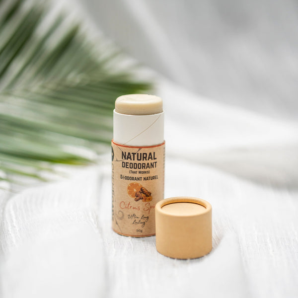 Natural deodorant stick with citrus spice scent, eco-friendly packaging on white fabric with palm leaf background